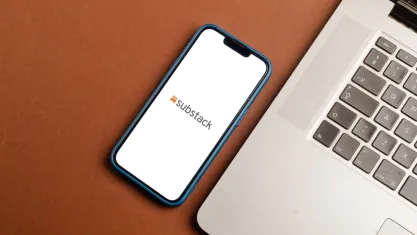 Substack logo on a phone beside a laptop